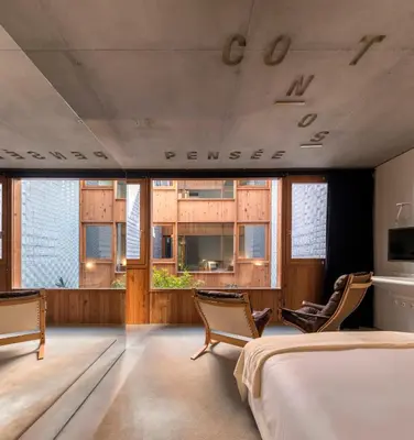a bedroom with a bed and chairs and windows at Hotel Tipografia do Conto by Casa do Conto in Porto