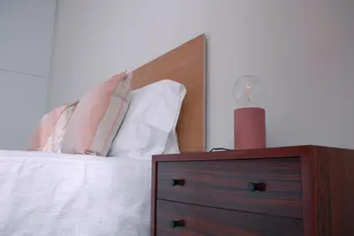 a bed with a wooden headboard and a night stand with a candle at Amazing City Center Apartment Porto Villa Lóios in Porto