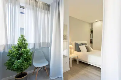 a bedroom with a bed and a chair and a plant at Downtown Porto Spot in Porto