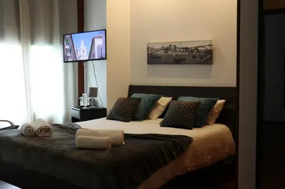 a bedroom with a bed with a tv on the wall at Metro Heroismo Residence in Porto