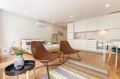 a bedroom with a bed and two chairs and a table at Oporto Palace Apartments in Porto