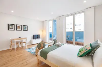 a white bedroom with a large bed and a table at Oporto Palace Apartments in Porto