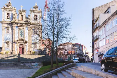 an old building with a tree in front of a street at Aposentus -Romantic Mezzanine Apartment With a Balcony in Porto