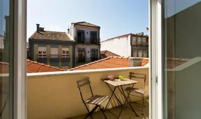 a balcony with two chairs and a table on a roof at A da Maria Ildefonso in Porto