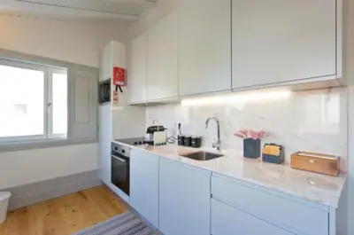 a kitchen with white cabinets and a sink and a window at A da Maria Ildefonso in Porto