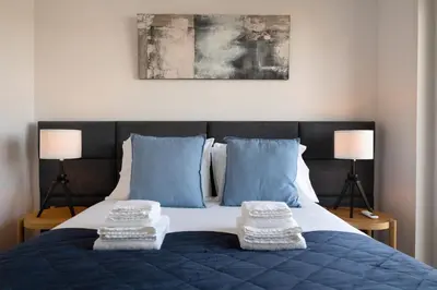 a bed with blue and white pillows and two lamps at Poveiros Terrace - 3BR Downtown apartment with AC in Porto