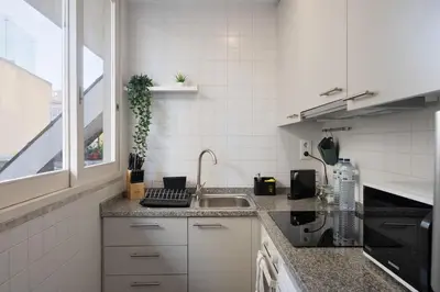 a white kitchen with a sink and a window at Poveiros Terrace - 3BR Downtown apartment with AC in Porto