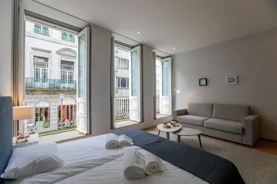 a bedroom with a bed and a couch and windows at Santa Catarina Downtown I in Porto
