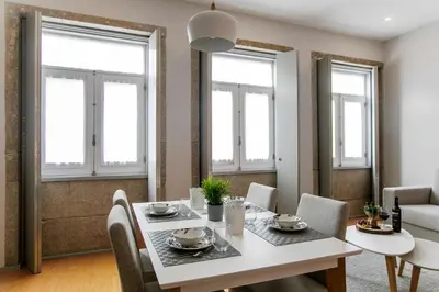 a dining room with a table and chairs and windows at Santa Catarina Downtown II in Porto