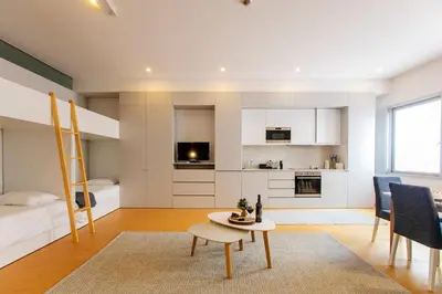 a bedroom with a bunk bed and a living room with a table at Santa Catarina Downtown III in Porto