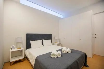 a bedroom with a bed with a pair of shoes on it at Santa Catarina Downtown III in Porto