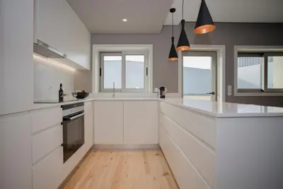 a white kitchen with white cabinets and windows at Alegria Residence in Porto