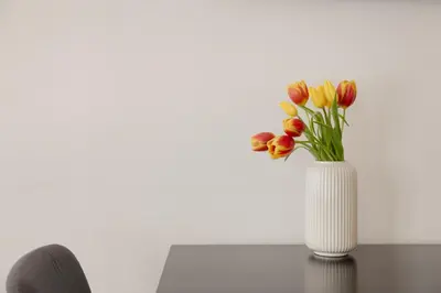 a white vase filled with red and yellow tulips at CASA JOY Boavista apartment in Porto