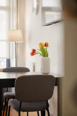 a table with two chairs and a vase with flowers on it at CASA JOY Boavista apartment in Porto