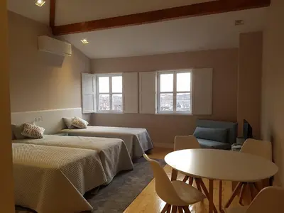 a room with two beds and a table and chairs at The Porto Way in Porto