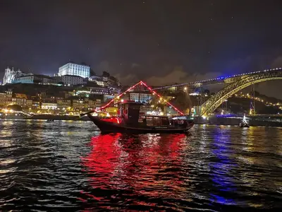 a boat in the water with a bridge at night at SLEEPBOAT Barco Hotel in Porto