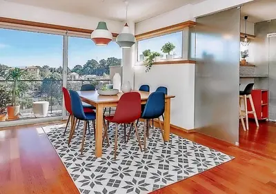 a dining room with a table and chairs on a rug at Charming Bonfim Penthouse in Porto