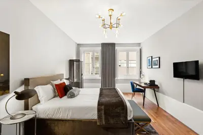 a bedroom with a bed and a desk and a television at The White Box Boutique House in Porto