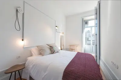 a room with two large windows and a blue couch at Tripas-Coração, Sá da Bandeira in Porto