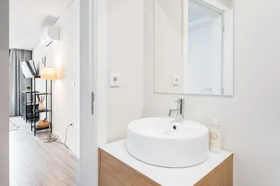 a white bathroom with a sink and a mirror at General Torres Apartments by Lisbeyond in Vila Nova de Gaia