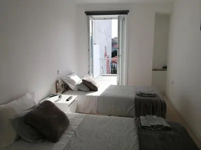 two beds in a small room with a window at Casa Ventuzelo in Porto