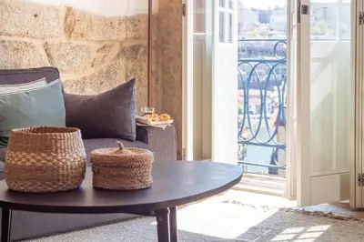 a bedroom with a white bed and a stone wall at LovelyStay - Sao Domingos Apartment in Porto