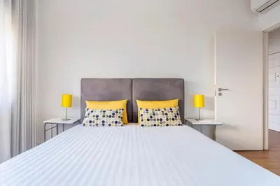 a bedroom with a large white bed with yellow pillows at Luxury Anibal Cunha Apartments in Porto