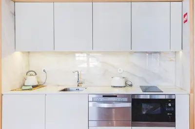 a kitchen with white cabinets and a stainless steel appliance at APOSENTUS - Charming Center Apartment with Balcony in Porto