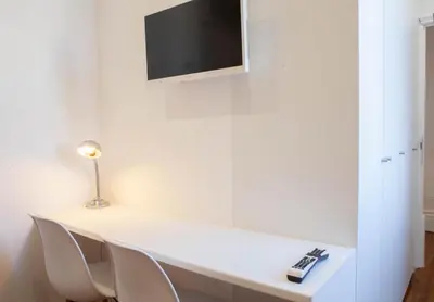 a white desk with chairs and a tv on a wall at PORTO CONCEPT HOME - Paranhos in Porto