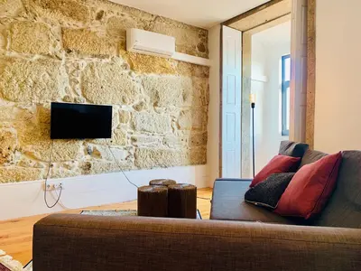 a living room with a couch and a stone wall at Oporto Chic&Cozy - Santo Ildefonso in Porto