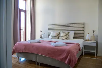 a white bedroom with a large bed and a window at Sweet Swell in Porto