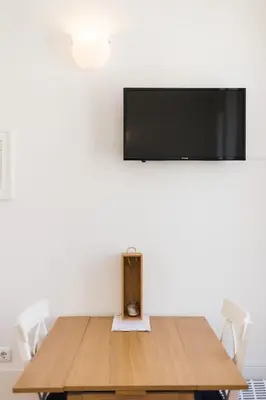 a table with chairs and a tv on a wall at VIVA Breiner Flats in Porto