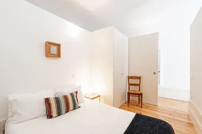a white bedroom with a bed and a chair at VIVA Breiner Flats in Porto