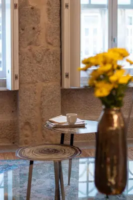 a vase with yellow flowers sitting next to a table at LovelyStay - Aurora Mezzanine in Porto
