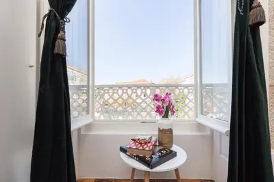 a vase of flowers on a table in front of a window at Host Wise - Charming Flat with Netflix - River View in Porto
