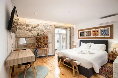 a bedroom with a large bed and a stone wall at Tito Studio Terrace in Porto