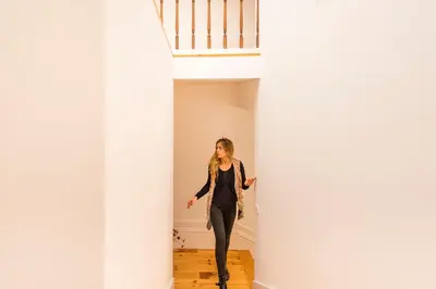 a woman walking down a hallway between white columns at Almada Luxurious Duplex by DA'HOME in Porto