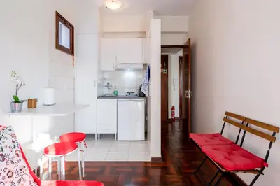 a living room with red chairs and a kitchen at Cozy Apartment Alegria Balcony in Porto