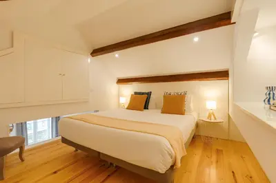a bedroom with a large white bed with orange pillows at DA'HOME - Vitoria Duplex Apartment in Porto