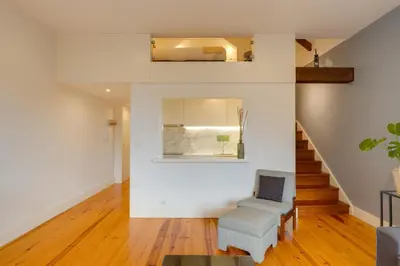 a living room with a chair and stairs at DA'HOME - Vitoria Duplex Apartment in Porto
