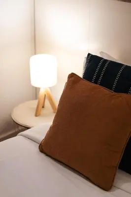 a bed with a brown pillow and a table with a lamp at DA'HOME - Vitoria Duplex Apartment in Porto