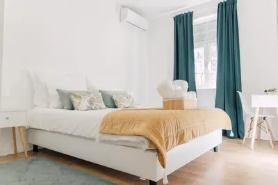 a bedroom with a white bed with green curtains at Oporto Yellow Villas in Porto