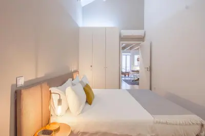 a bedroom with a bed with white sheets and pillows at Comercio RIBEIRA Luxury Penthouse Apartment in Porto