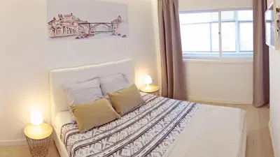 a bedroom with a bed with two lamps and a window at São João Oporto Residence I & II in Porto