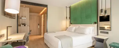 a bedroom with a white bed and a green wall at NH Porto Jardim in Porto