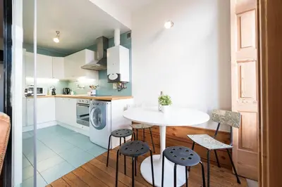 a kitchen with a white table and stools at Fontainhas Design Apartment by DA'HOME in Porto