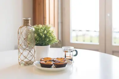 a table with a plate of cupcakes and a glass bottle at Fontainhas Design Apartment by DA'HOME in Porto