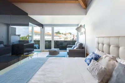 a bedroom with a large bed and a living room at Fontaínhas Stylish Apartment by DA'HOME in Porto