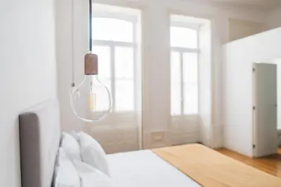 a bedroom with a white bed and a light fixture at O da Joana in Porto