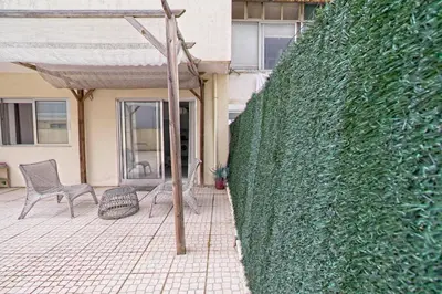 a patio with two chairs and a green wall at Gaia Central Apartment in Vila Nova de Gaia